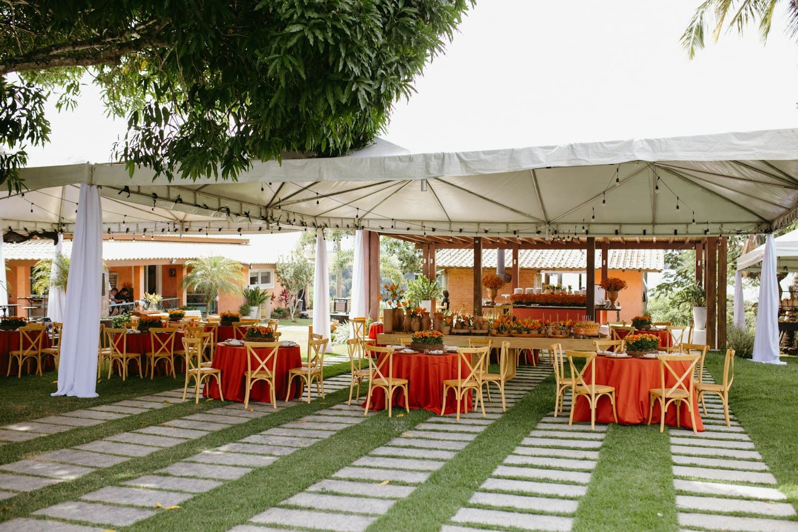 An outdoor event set up with tents, tables and chairs on the grass.