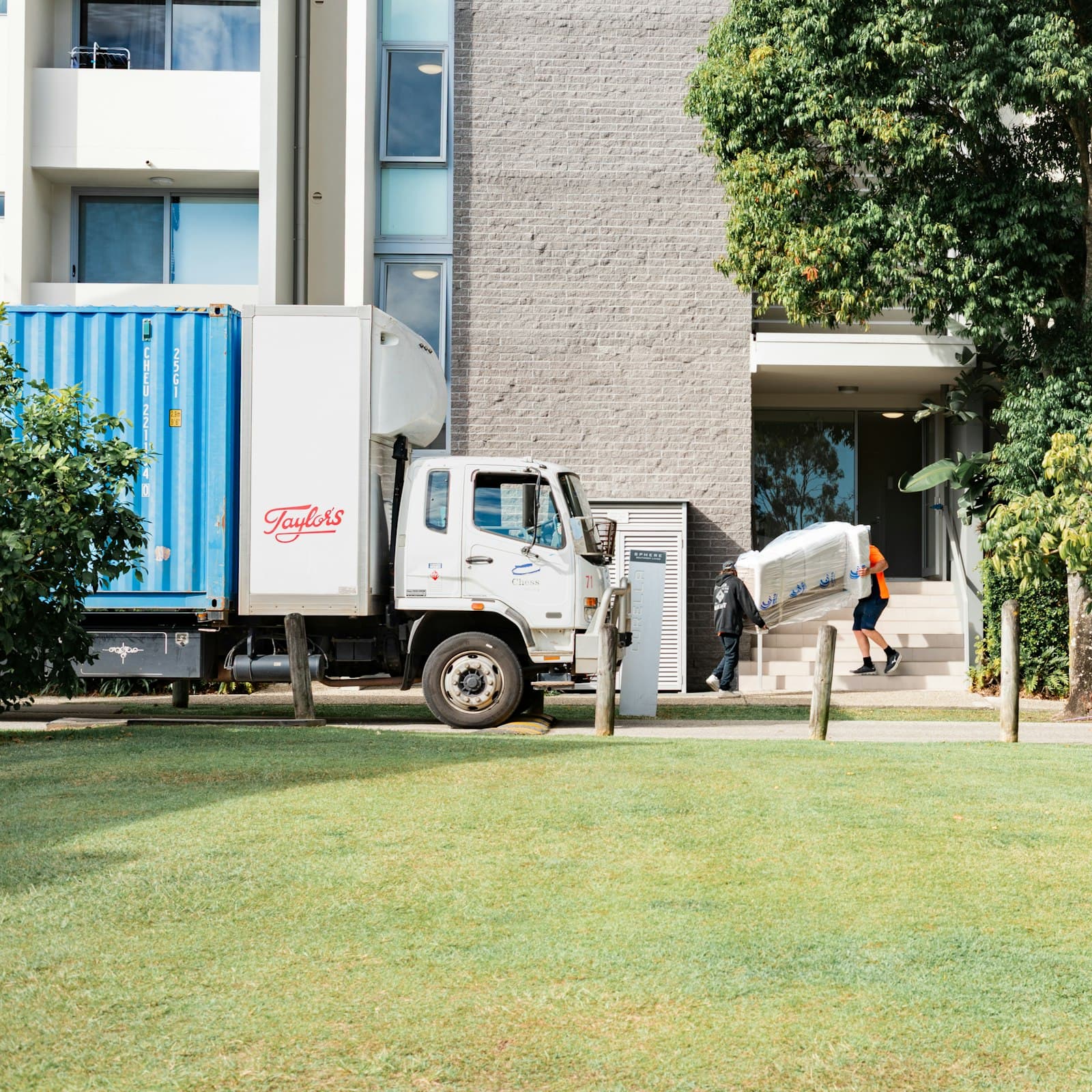 A mover carrying furniture next to a moving truck.