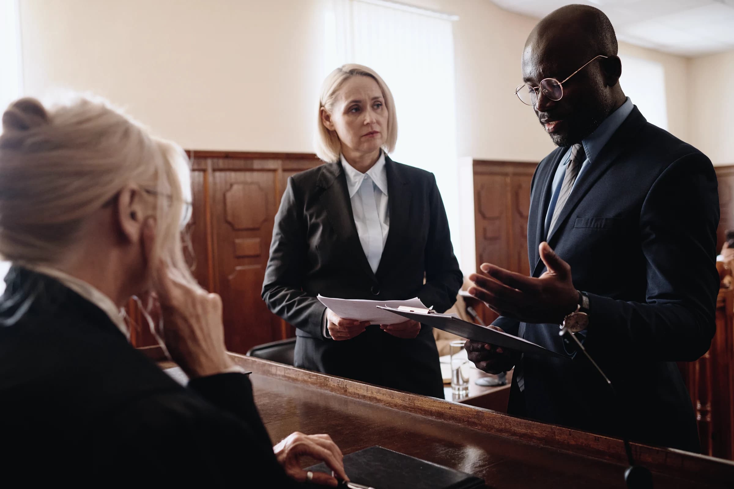 Lawyers consulting with a client at a podium in a courtroom