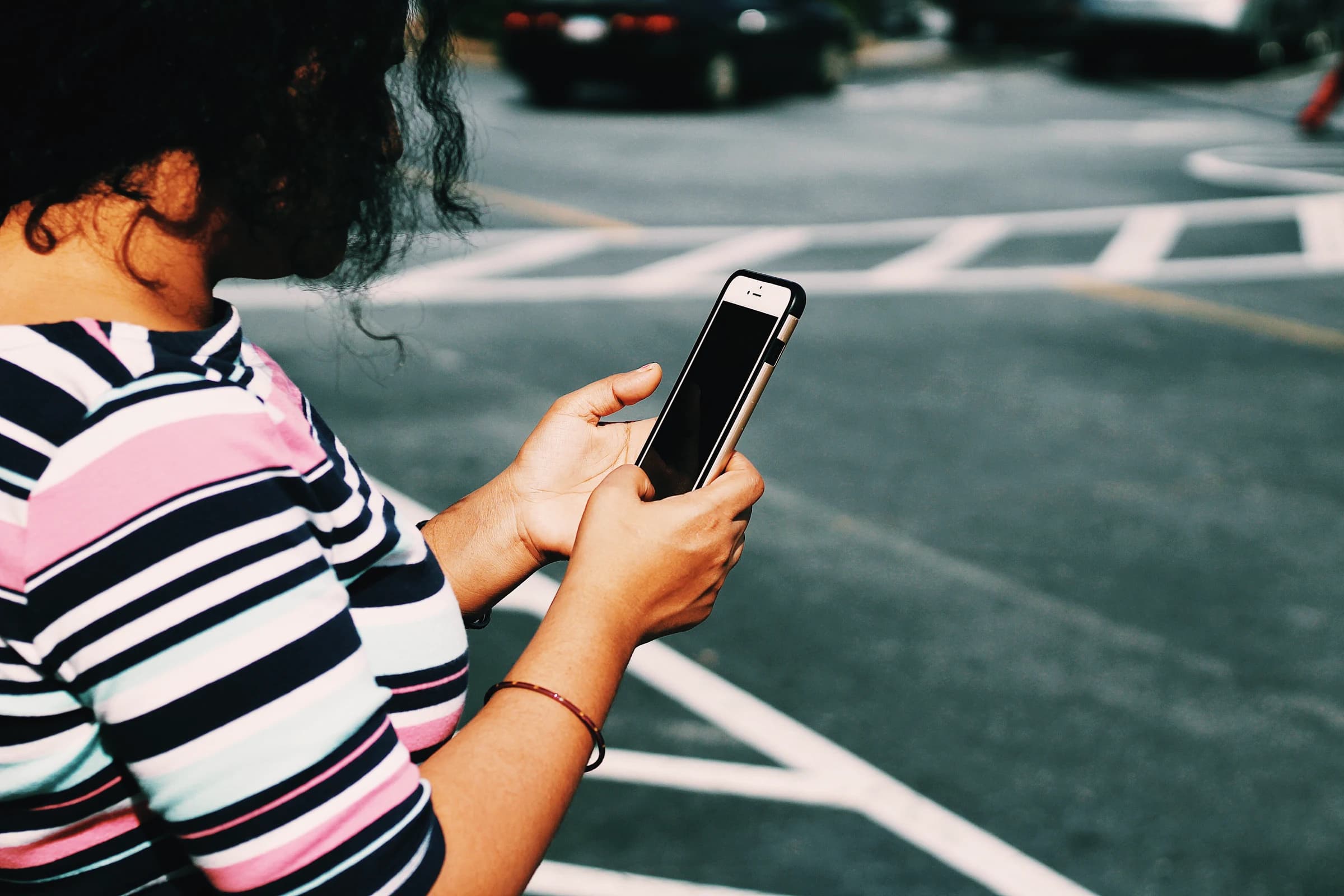 A woman using her phone while crossing a city street
