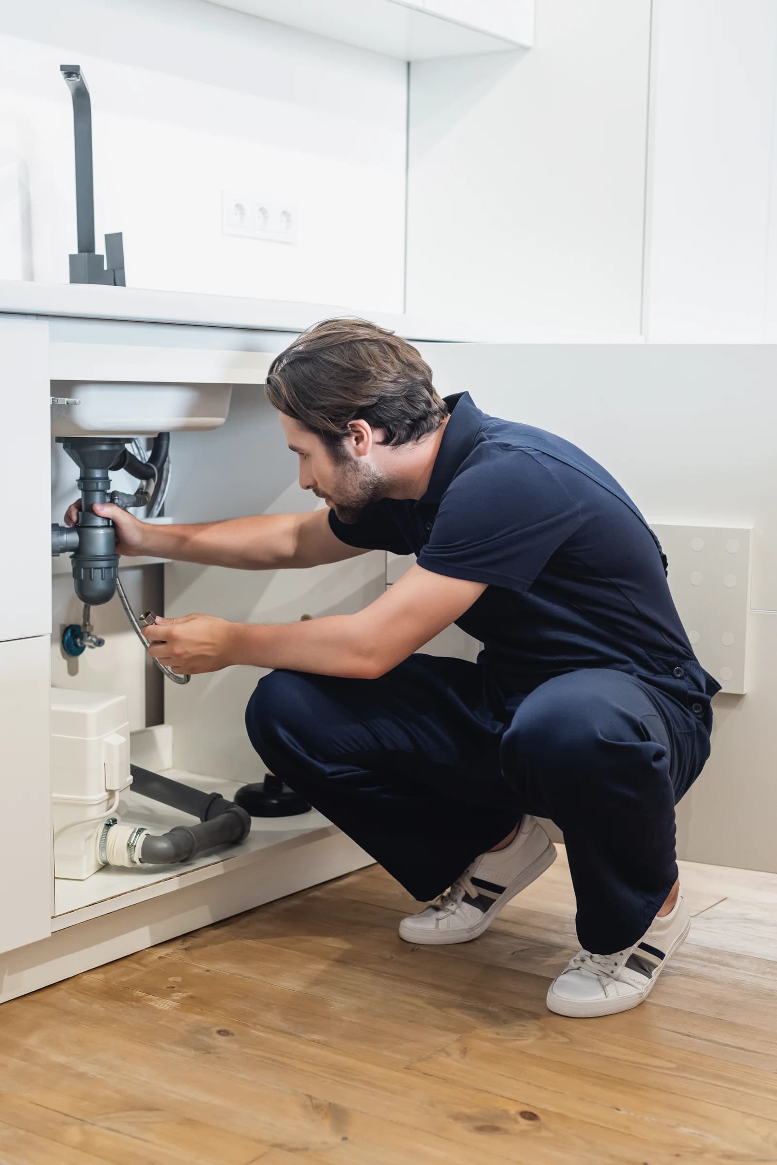 Plumber working under a sink repairing pipes